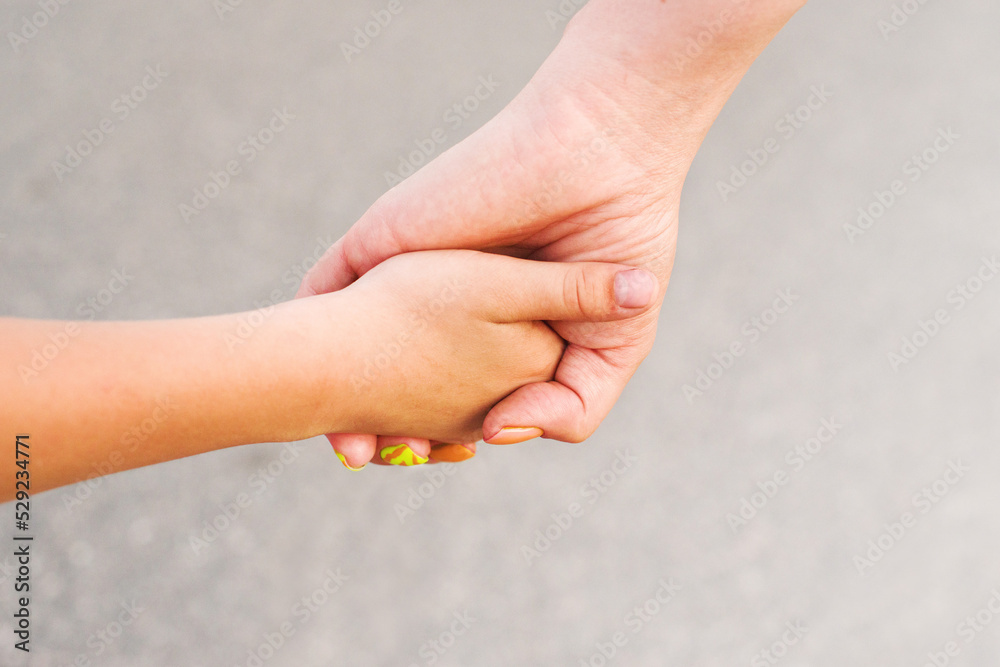 Child's hand holds mother's hand, close-up. Family scene, child care, support and guardianship Child's hand holds mother's hand, close-up. Family scene, child care, support and guardianship