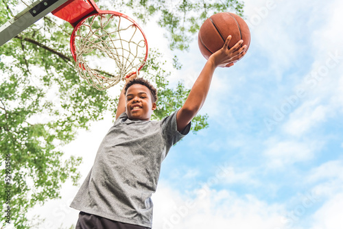 portrait of a boy kid playing with a basketball in park