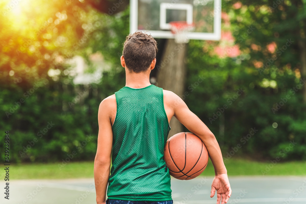 portrait of a boy kid playing with a basketball in park view from back portrait of a boy kid playing with a basketball in park view from back