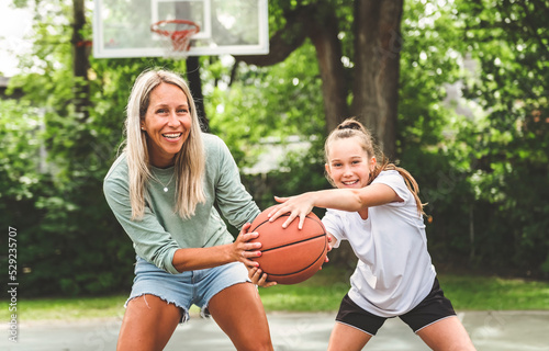 Mother and little daughter play basketball outside
