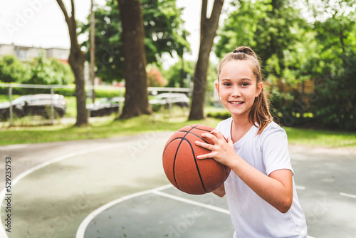 girl with basketball on court on summer season