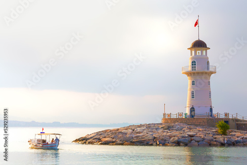фотографія The old lighthouse and fishermen boat in the port of the Turkish city of Alanya at sunrise