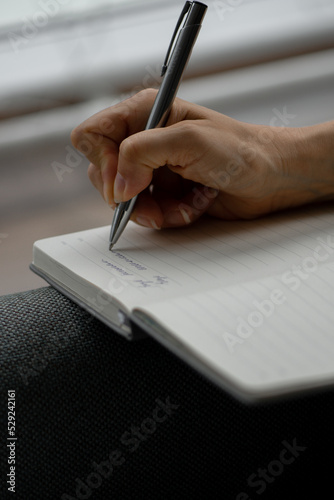 A woman's hand makes notes in a diary, a business woman negotiates, signs important documents in the office