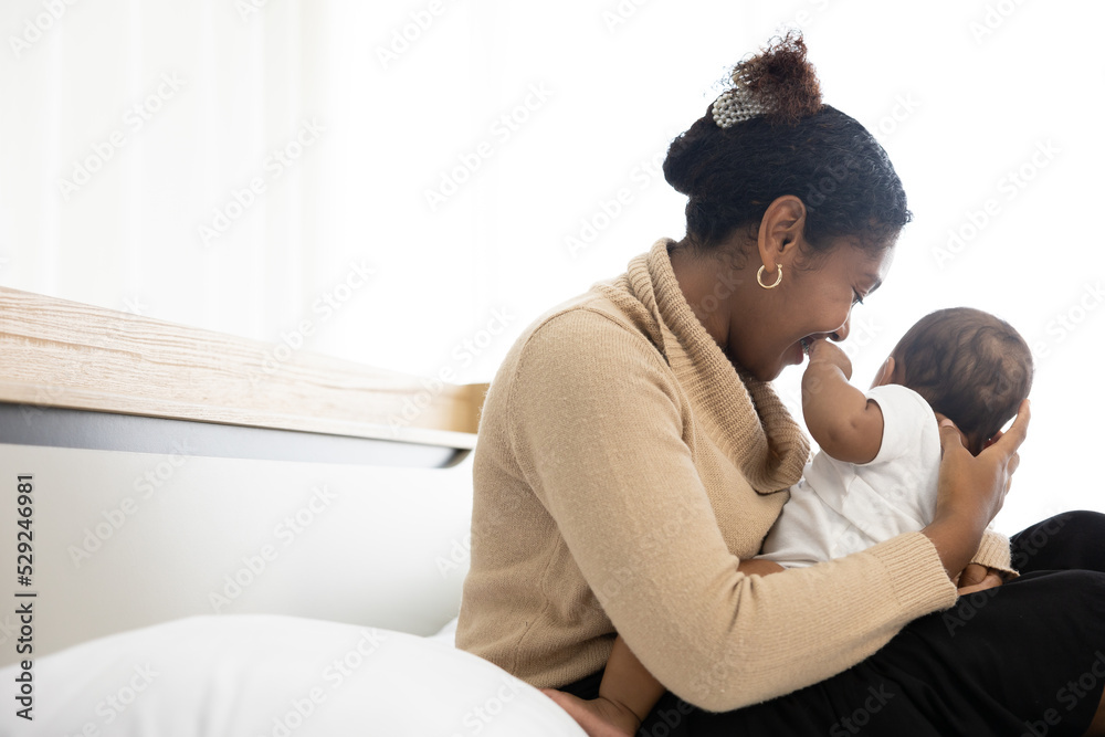 African young mother hugging and playing with her adorable baby on bed African young mother hugging and playing with her adorable baby on bed