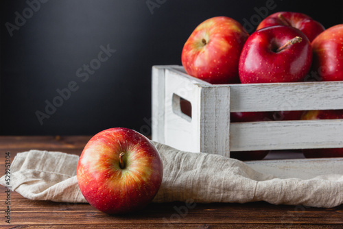 Red apples in a crate on a wooden background