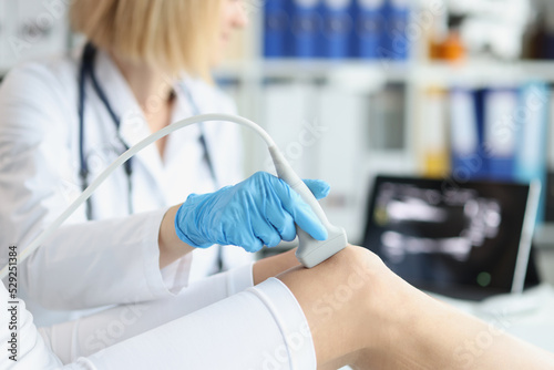 Orthopedic doctor makes ultrasound examination of patient knee in office