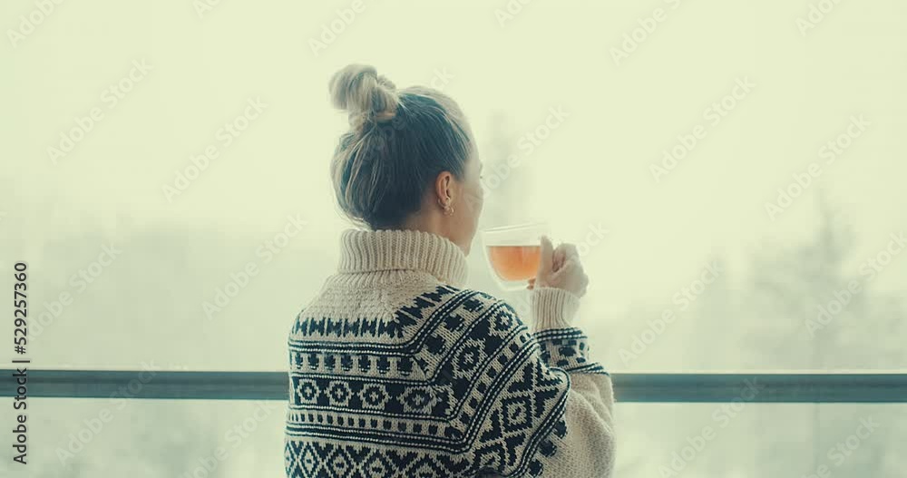 Woman drinks tea, and relax on terrace at home in winter day. Health care, authenticity, sense of balance and calmness. Fresh air, It's Snow time. 4K Video
