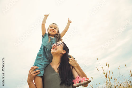 child girl with mother are playing in wheat field.