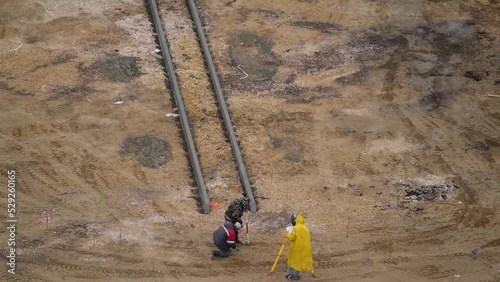 A surveyor in a yellow raincoat works at a construction site. photo