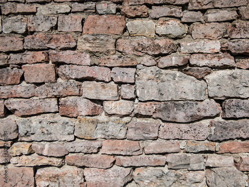 View of empty, old white, pink and grey brick wall background with copy space. A deteriorating old brick wall outdoors in sunlight