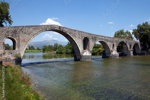 The Bridge of Arta. A stone bridge that crosses the Arachthos river in the west of the city of Arta in Greece. Sunny day with blue sky