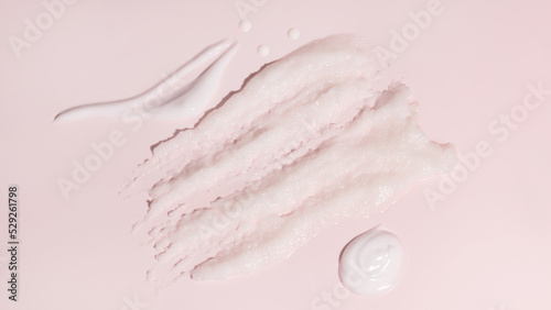 Sample beauty products for facial skin care on pink background. Cleanser foam, tonic, oil serum essence drop and moisturizer cream smear