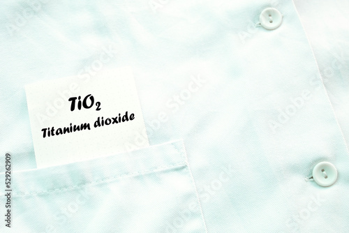 A piece of paper with TiO2 titanium dioxide written on it appears from a poket of a laboratory coat. photo