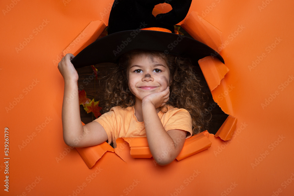 Laughing funny child girl in a witch costume in halloween