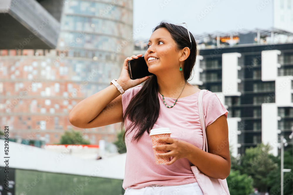 Happy ethnic female smiling while talking phone on street Happy ethnic female smiling while talking phone on street