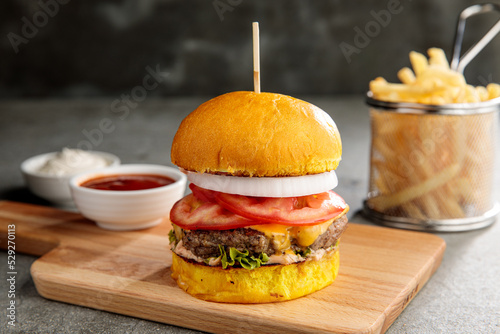 Foto classic chicken burger with ketchup and fries isolated on cutting board side vie
