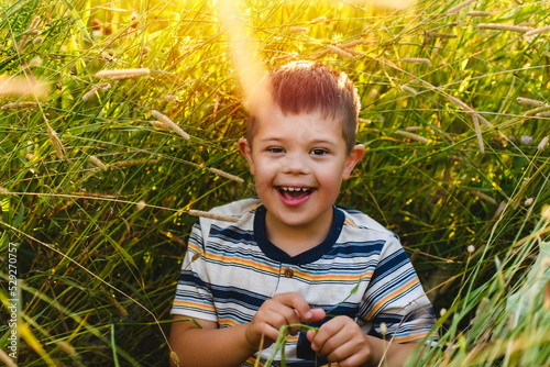 Portrait of a little boy with down syndrome in sunset on summer season