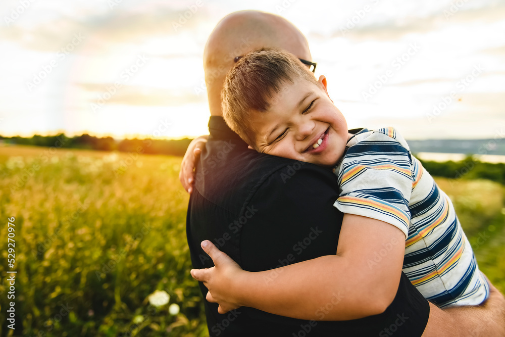 Portrait of a little boy with down syndrome in sunset on summer season with his father Portrait of a little boy with down syndrome in sunset on summer season with his father
