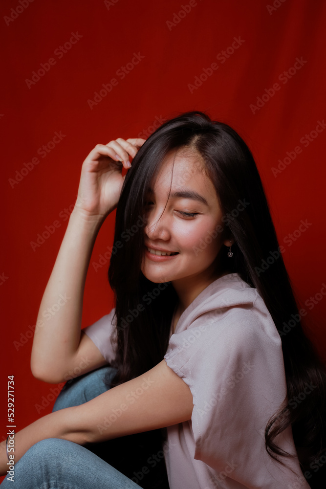 Obraz premium Asian woman taking photo on a red background. Happy Asian woman. Beautiful asian woman with long and straight hair.