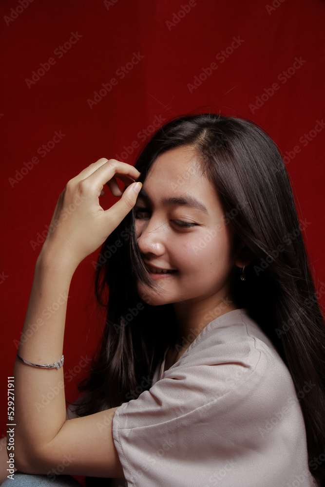 Obraz premium Asian woman taking photo on a red background. Happy Asian woman. Beautiful asian woman with long and straight hair.