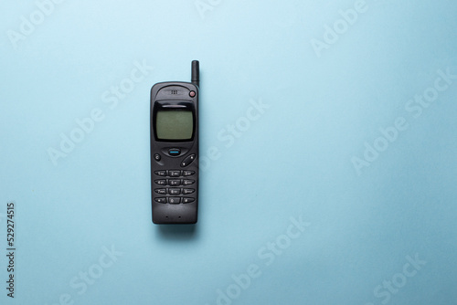 A vintage mobile phone from the 1990s isolated on a blue background.