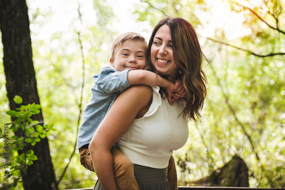 Portrait of a little boy with down syndrome while playing in a park with his mother Portrait of a little boy with down syndrome while playing in a park with his mother