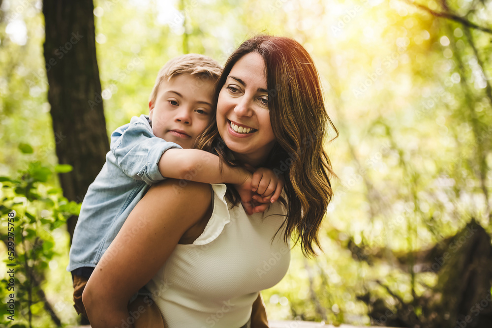 Portrait of a little boy with down syndrome while playing in a park with his mother Portrait of a little boy with down syndrome while playing in a park with his mother