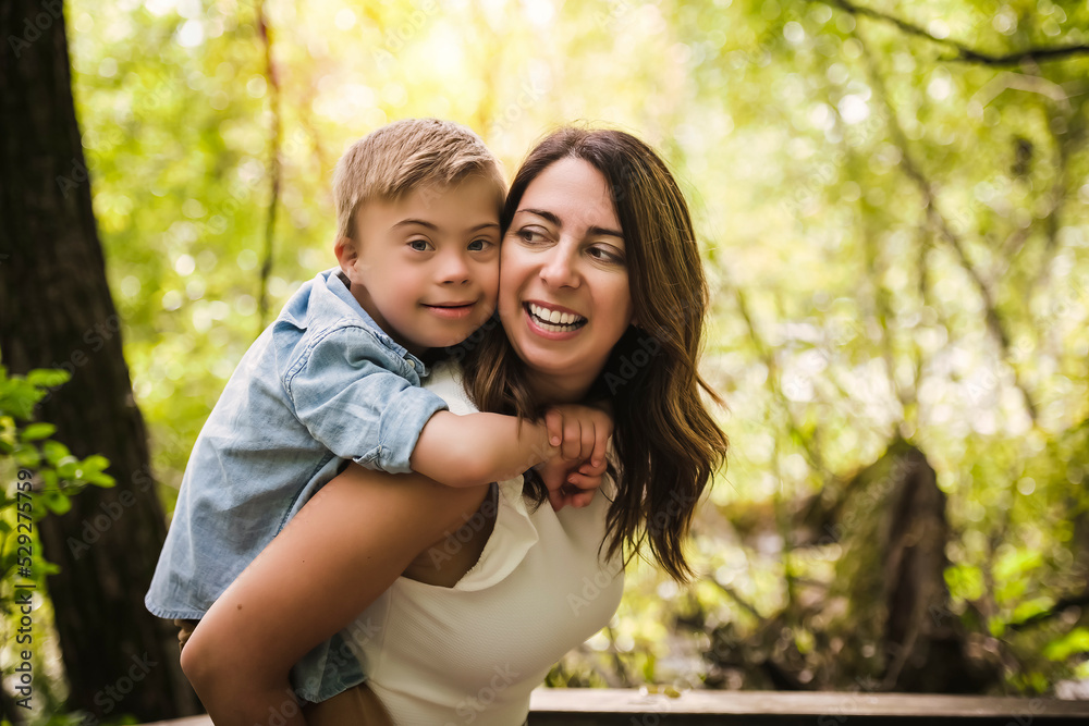 Portrait of a little boy with down syndrome while playing in a park with his mother Portrait of a little boy with down syndrome while playing in a park with his mother