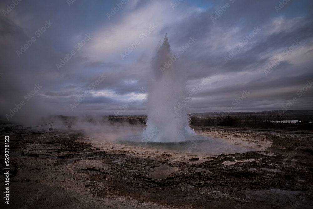 Geyser erupting hot spring against cloudy sky Geyser erupting hot spring against cloudy sky