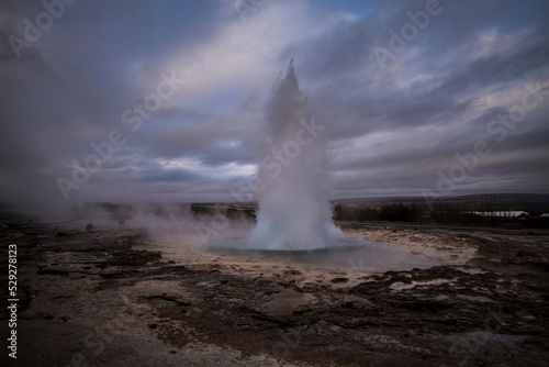 Geyser erupting hot spring against cloudy sky