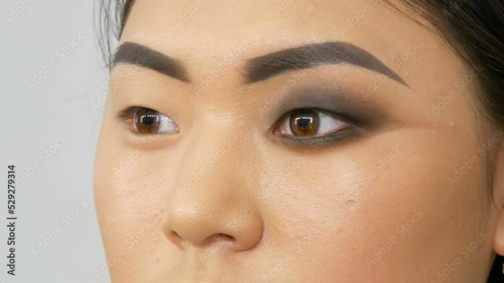 Professional make-up artist makes eye makeup of Korean girl Asian woman with special brush Professional make-up artist makes eye makeup of Korean girl Asian woman with special brush