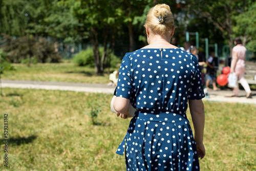 Polka dot dress. Woman in park. Girl walks down street.