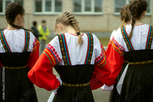 Girl in Russia in folk dress. Preparation for dance. Children perform on street with theatrical number.