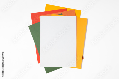 Blank paper mockup on white table. Colorful paper. Flat lay, top view, copy space
