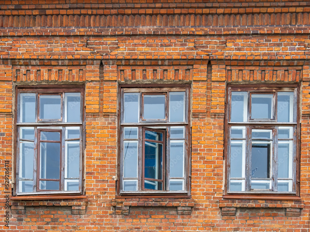 Three windows of the old mansion 19 century with brown bricks wall