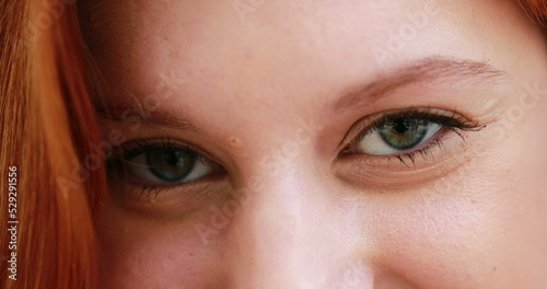 White girl opening eyes, closeup of young redhair woman with green eyes