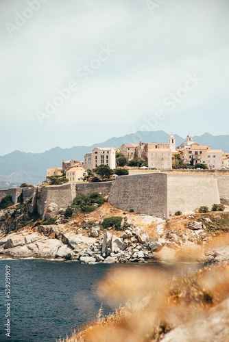 Vertical shot of the Citadel in Calvi Corsica with a waterscape and mountains in the background photo