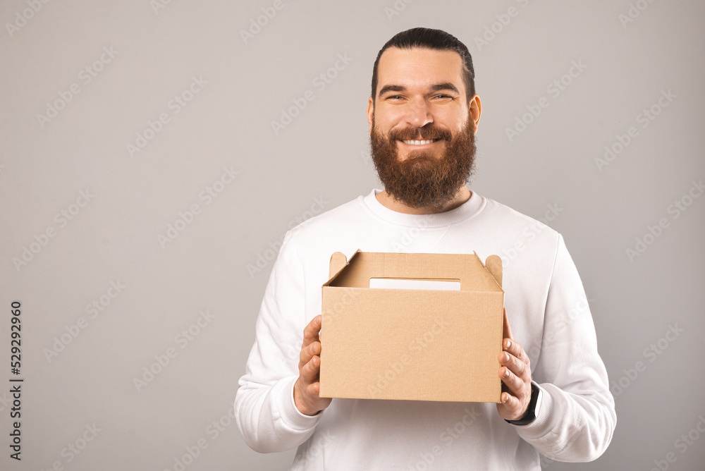 Friendly bearded man is holding delivery lunch box with copy space on it. Friendly bearded man is holding delivery lunch box with copy space on it.