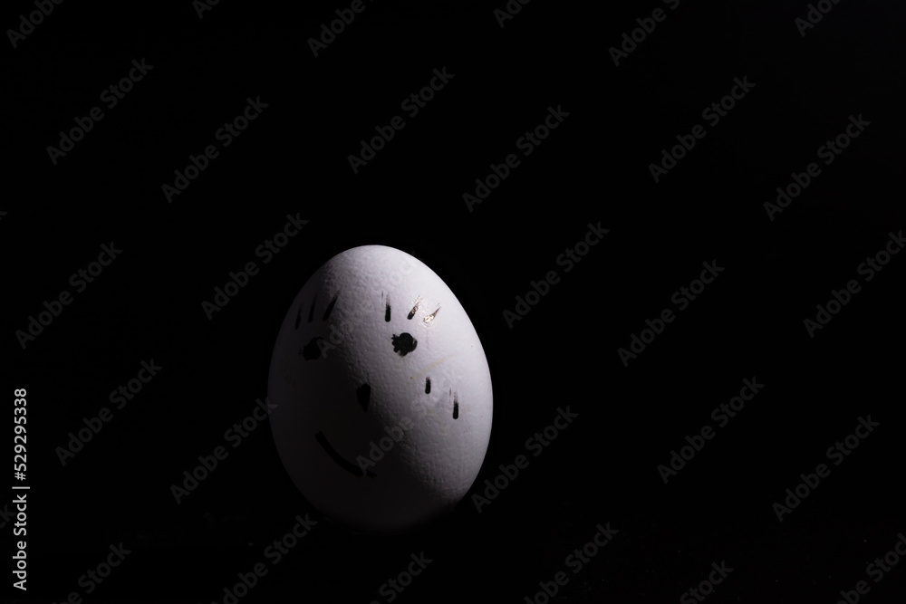 huevo de gallina de color blanco pintado de huevo de pascua, con la cara triste, sobre fondo negro, con gotas de agua en el suelo huevo de gallina de color blanco pintado de huevo de pascua, con la cara triste, sobre fondo negro, con gotas de agua en el suelo