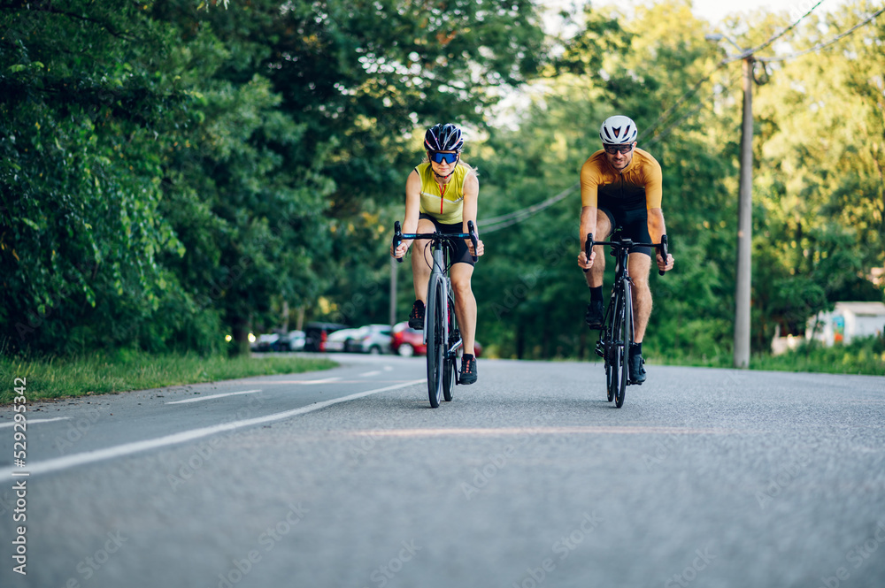 Obraz premium Couple riding road bicycles outside and wearing helmets and sunglasses
