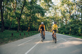 Couple riding road bicycles outside and wearing helmets and sunglasses