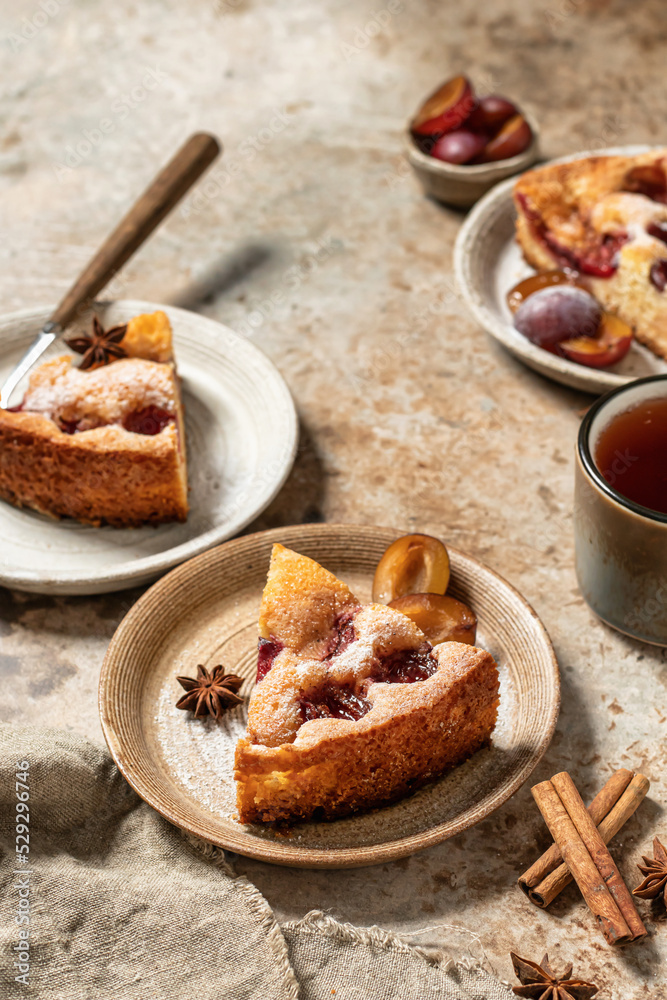 Pieces of The New York Times Famous Plum Torte or pie with spices and tea on textured background rustic style. Space for text