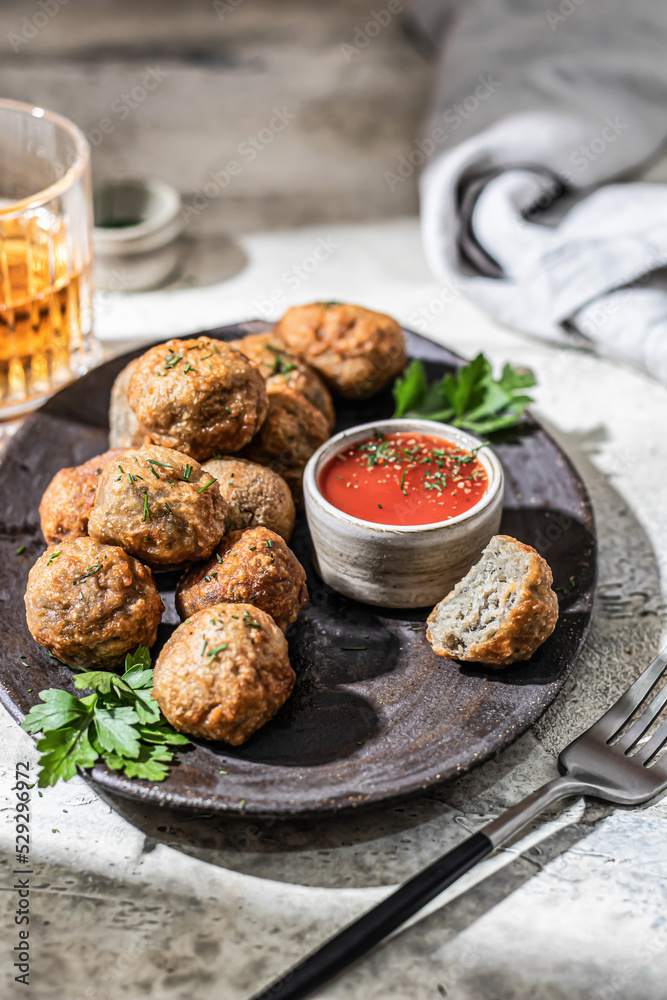 Cibriki potato fritters made from grated potatoes in balls form. Traditional Belarusian cuisine, served with sauce, herbs and cutlery in modern style with hard light and hadows. Photo for menu
