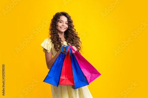 Shopping bags in the kids hands. Teen girl after shopping. Purchases, black friday, discounts and sale concept. Happy teenager portrait. Smiling girl.