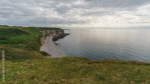 View at the Alabaster coast with beach Plage du Tilleul on a cloudy summer day, Etretat, Normandy, France