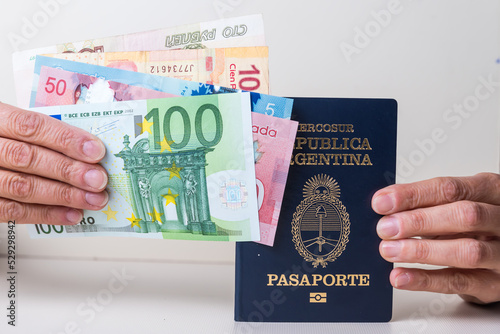 hands holding passport and several banknotes from different countries
