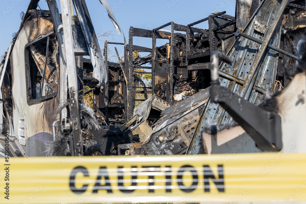 Burned out RV motorhome interior from a fire or explosion or fire bomb or arson shows the melted interior and the devastation of the accident.  Yellow caution tape,