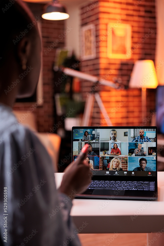 Fototapeta premium Businesswoman chatting with remote team on teleconference using laptop, back view. Company colleagues discussing business on videocall, office employees teamwork and cooperation