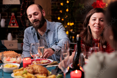 Couple celebrating christmas with family  talking at festive dinner table  eating traditional winter holiday meal  drinking sparkling wine. Xmas celebration at home party  wife and husband chatting