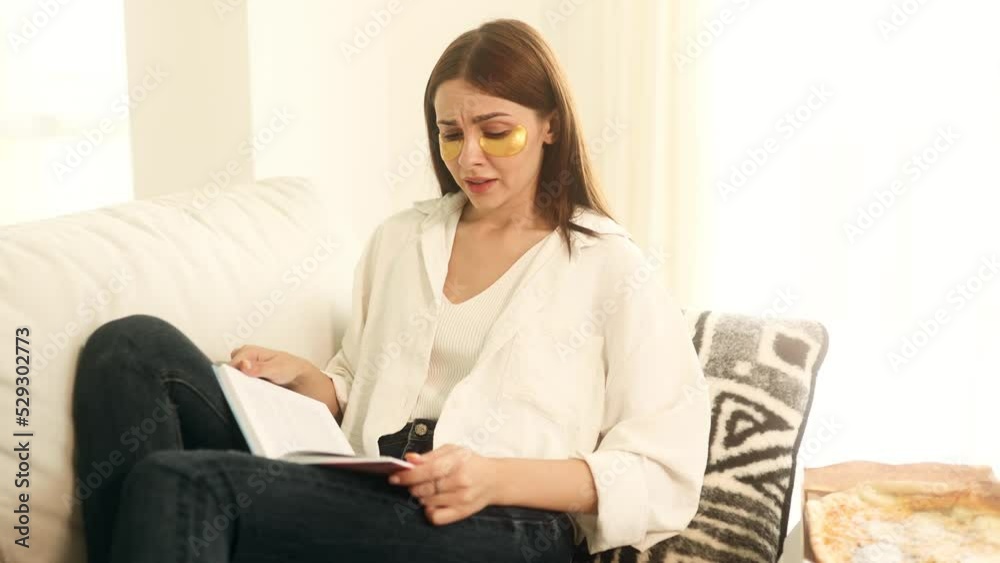 Boring young woman with patches under her eyes stops reading a book and picks up the phone checking her social media. Phone addiction. Boring young woman with patches under her eyes stops reading a book and picks up the phone checking her social media. Phone addiction.